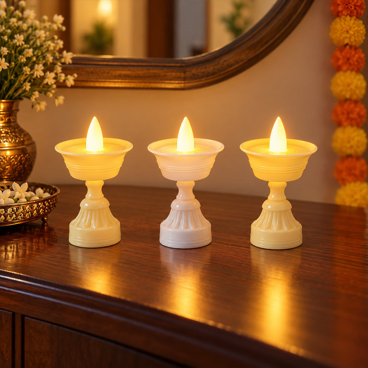 Three flameless LED diyas with warm yellow glow arranged on a dark surface