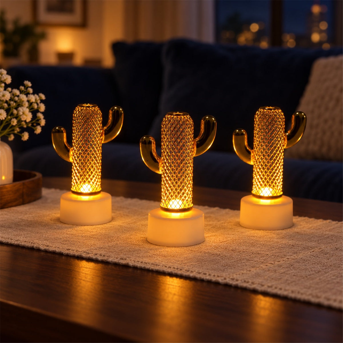 Three glowing gold cactus lights with white bases are displayed on a wooden coffee table with a white runner.
