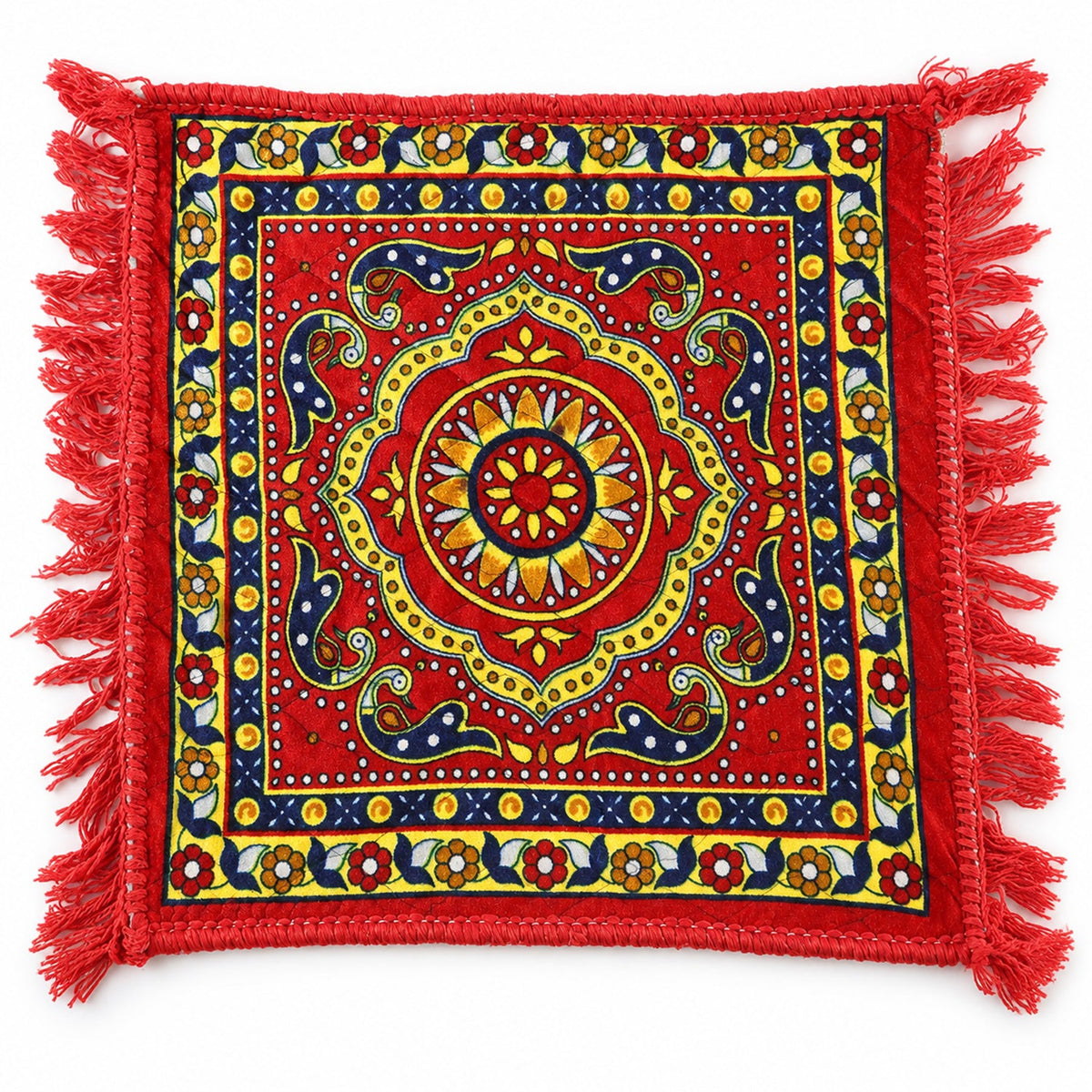 A square red prayer mat with a detailed yellow and blue traditional pattern and red fringe, viewed from above.