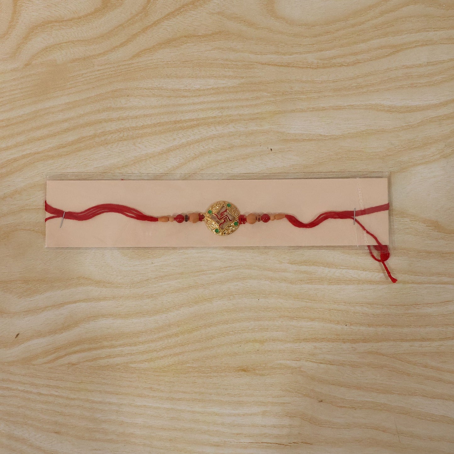 Swastik Rakhi with peach beads displayed on surface