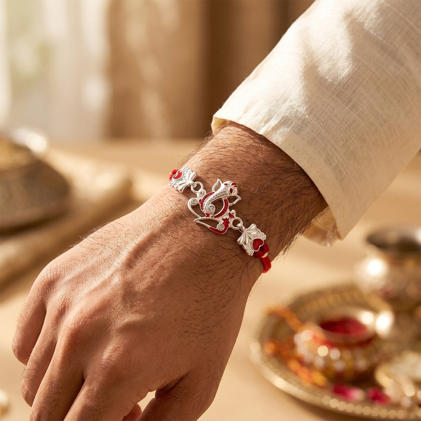 Close-up of the silver Ganesha motif with red heart stones on the designer rakhi.