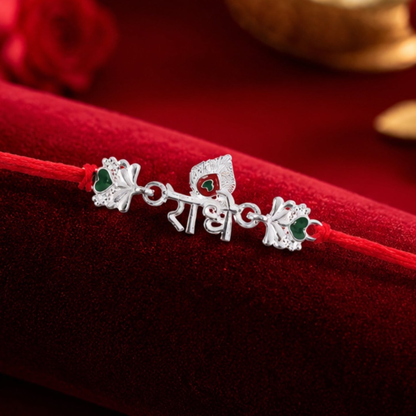 Close-up of silver rakhi centerpiece with green stones and red thread