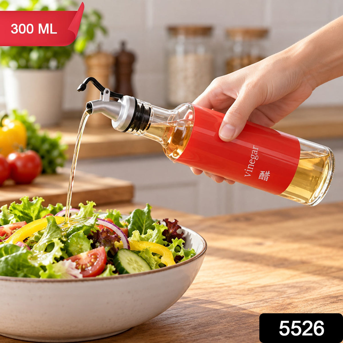 A hand holds a clear glass bottle with a red label, dispensing liquid over a colorful salad on a wooden table.