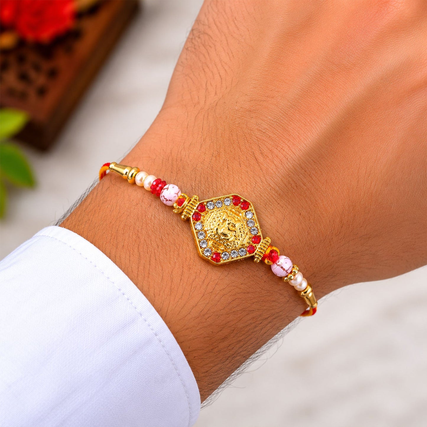Red-yellow thread and golden beads detail of Ganesh Rakhi