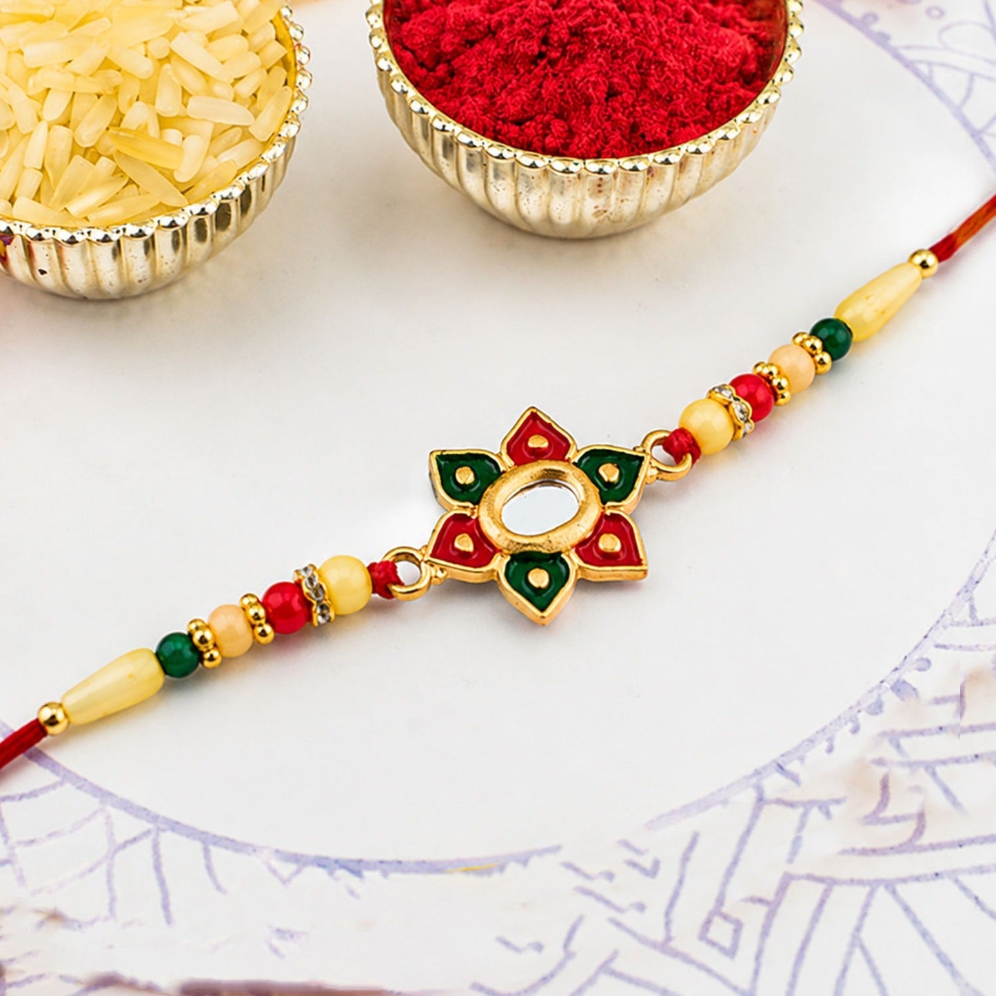 Floral Rakhi with multicolor stone work and beaded red thread on display