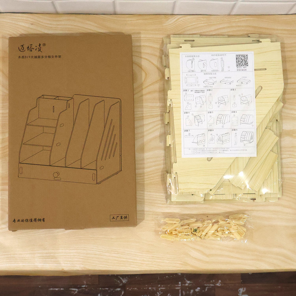 Brown cardboard box with a line drawing of the organizer next to the unassembled wooden pieces.