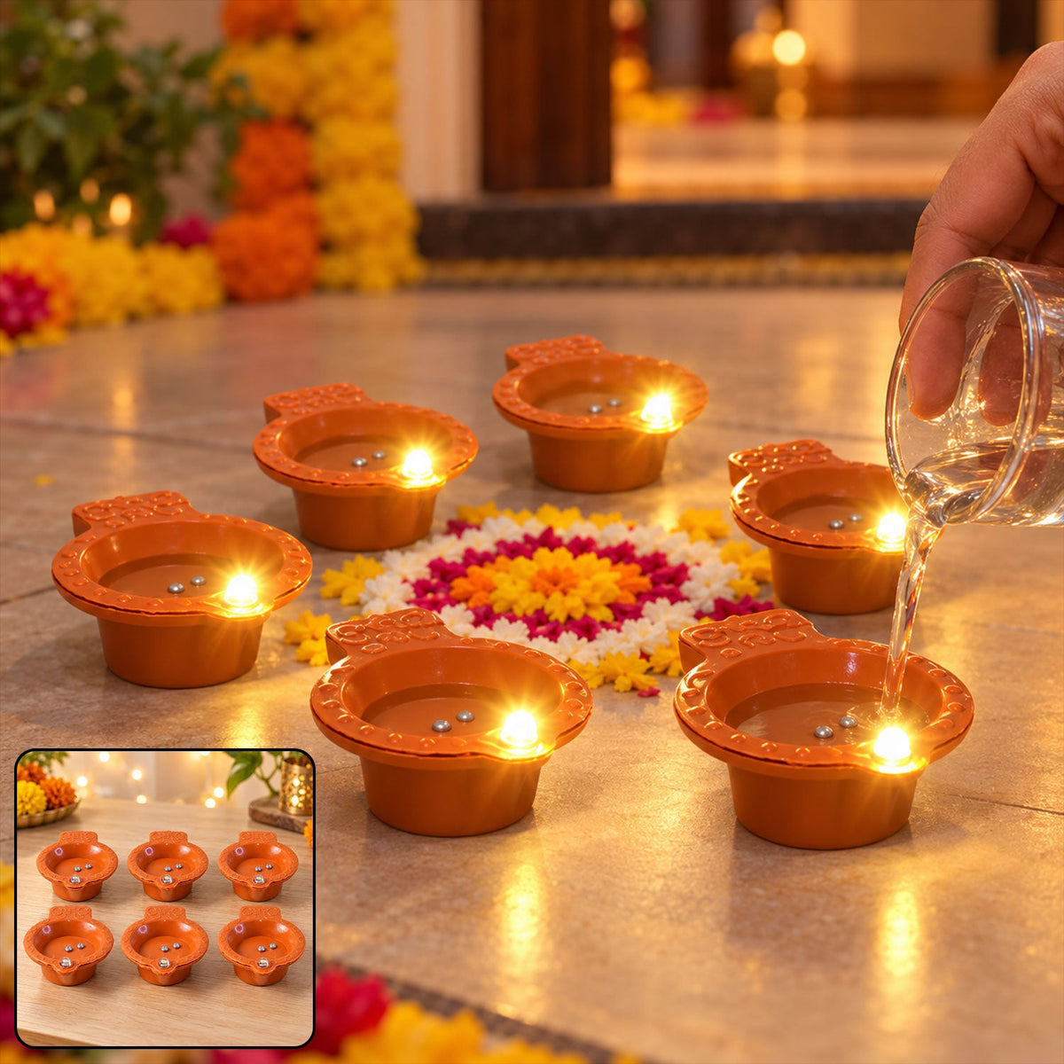 A hand pours water into one of six glowing orange diyas, arranged on a floor with a colorful floral design.