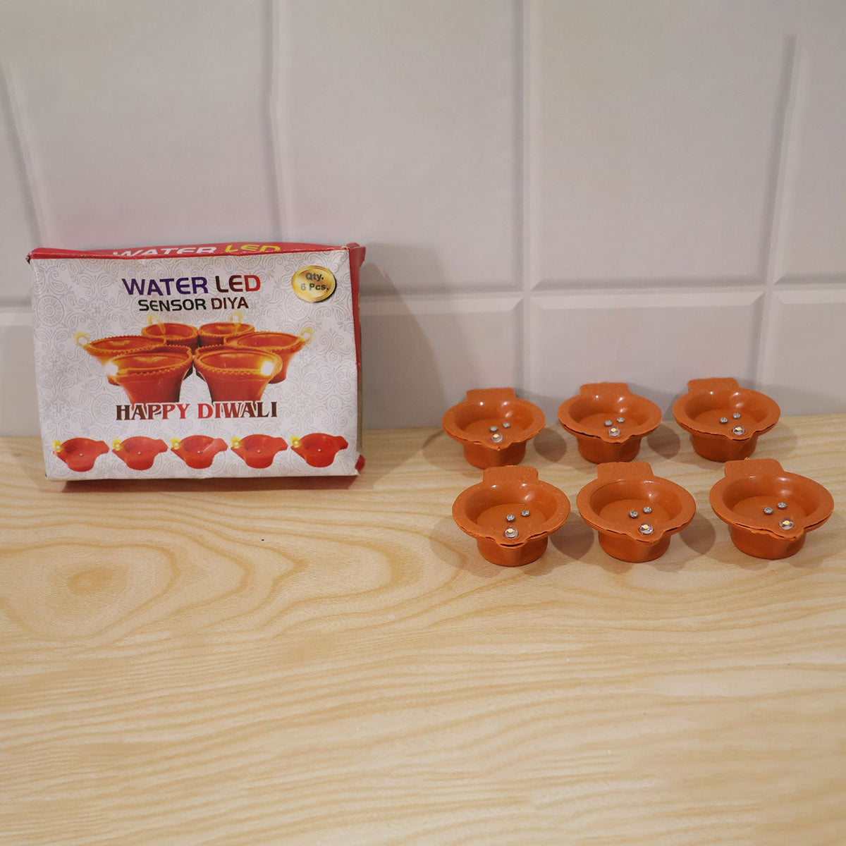 Water-activated LED diyas used in a pooja setting with flowers