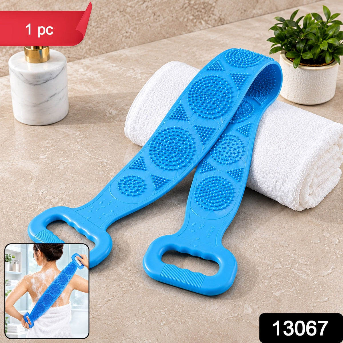 A blue silicone back scrubber with textured surfaces and handles rests on a white towel next to a soap dispenser. – view 2