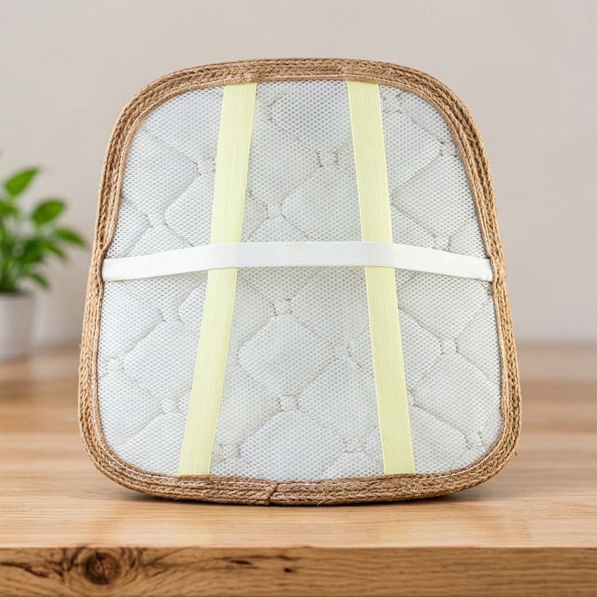 Back of the brown cushion revealing white mesh, quilted pattern, and light yellow elastic straps.