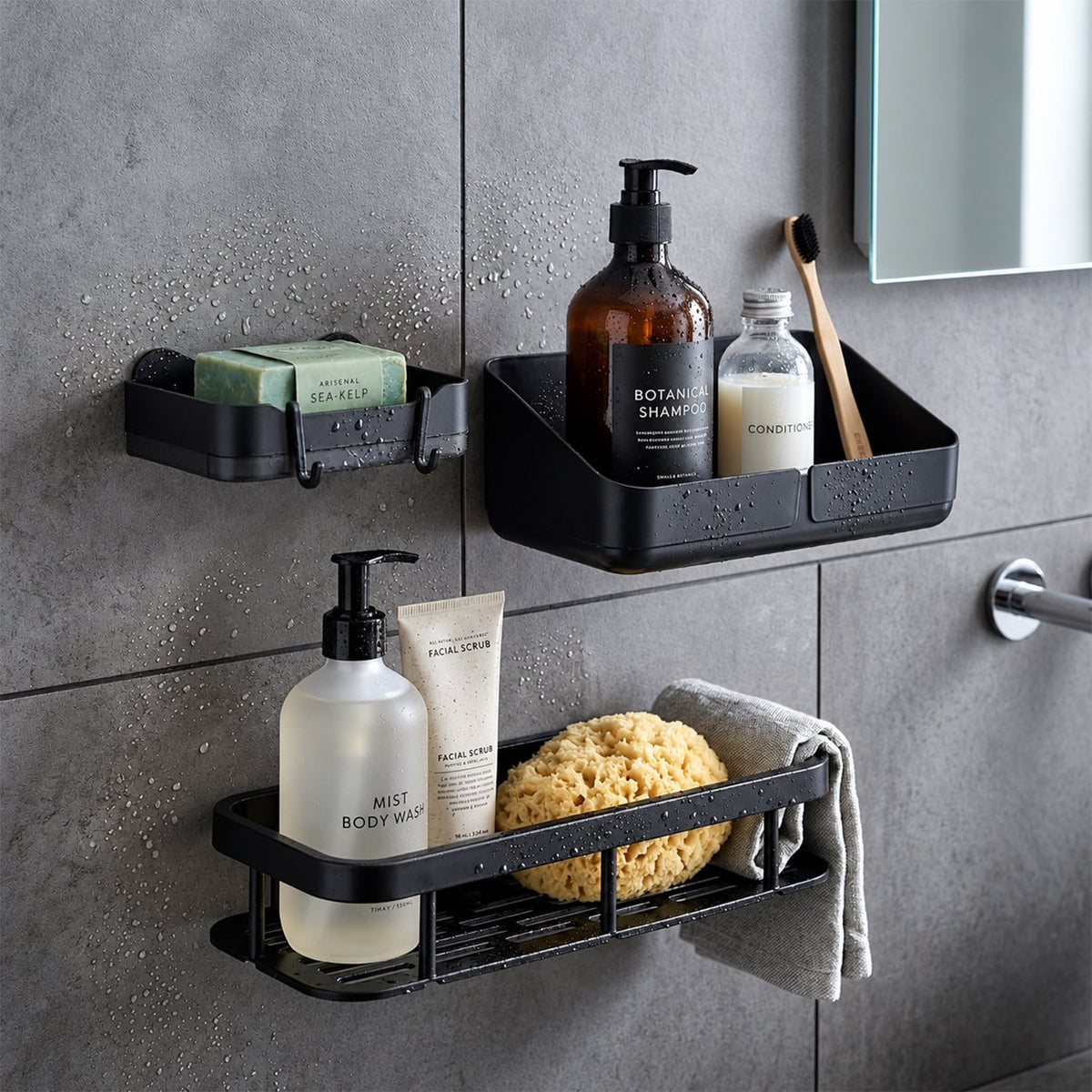 Three black plastic bathroom organizers, including a corner caddy, are mounted on a dark gray tiled shower wall.