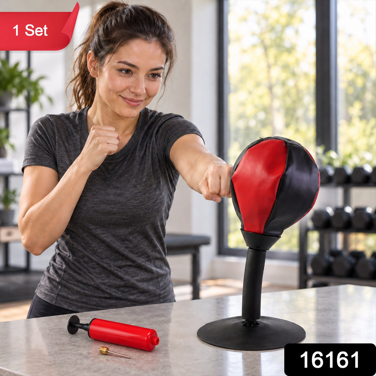 A woman in a grey shirt punches a red and black desktop punching ball on a counter, with a red pump and needle.