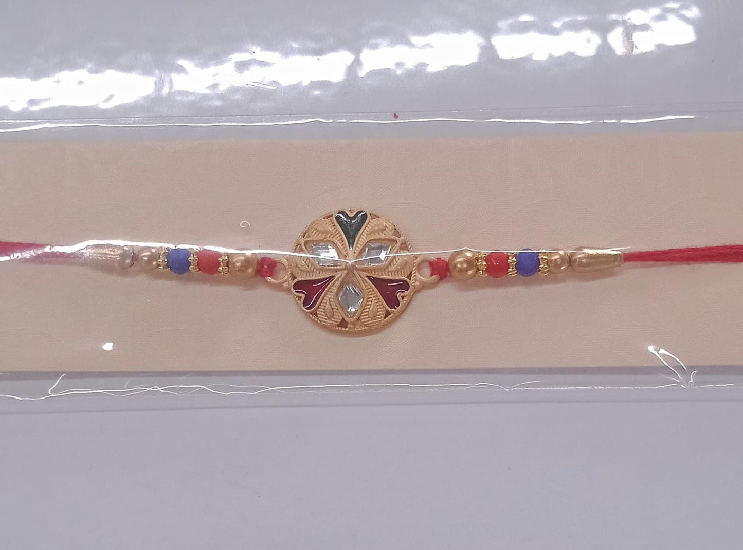 Red thread floral rakhi with mirror work and colorful beads detail