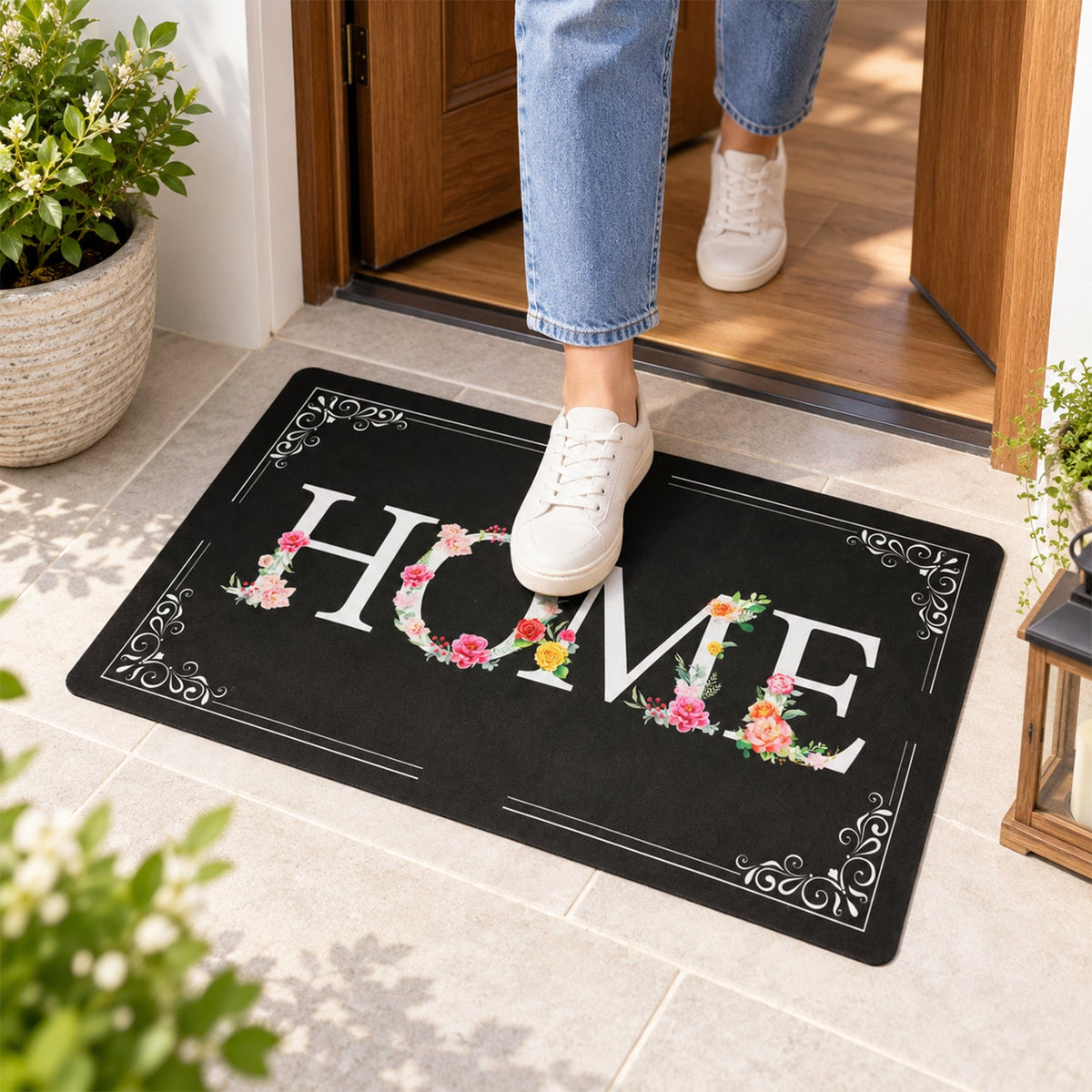 A person steps on a black rectangular mat with a white and floral HOME design at an entryway.