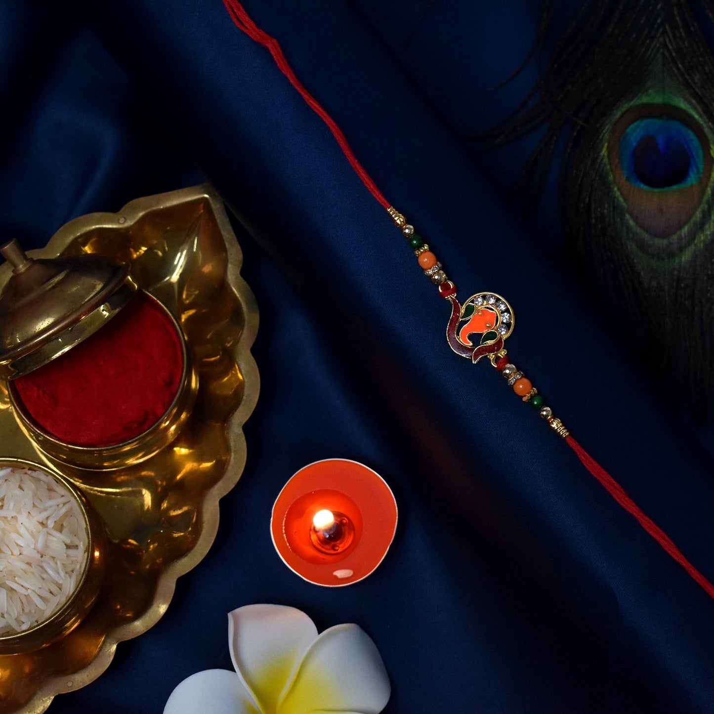 Golden Ganesha Rakhi with red and green beads and stone detailing