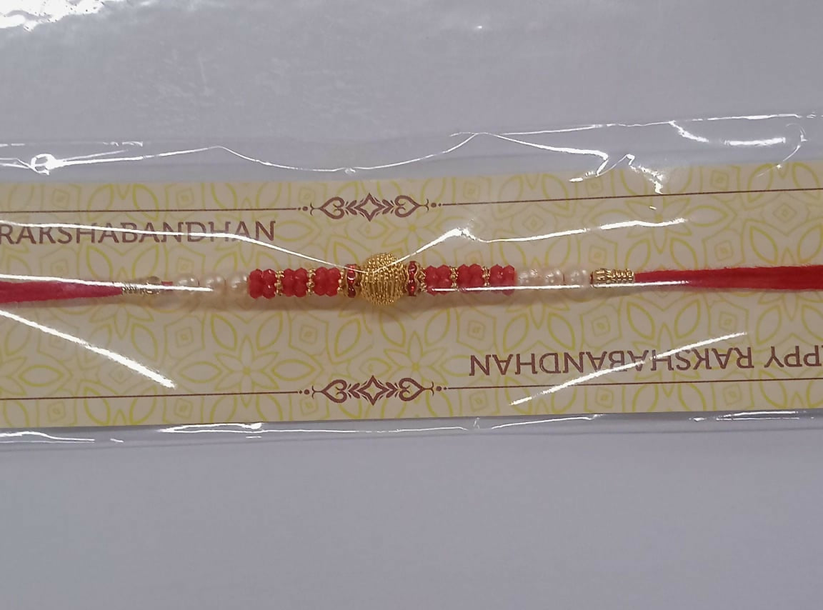 Traditional Red Bead Rakhi showing radiant golden centerpiece