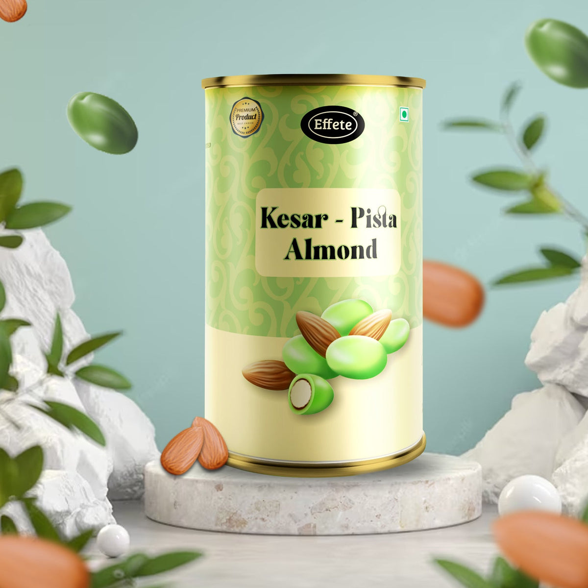 The Kesar Pista Almond tin is displayed on a light gray stone pedestal with white rocks and leaves.