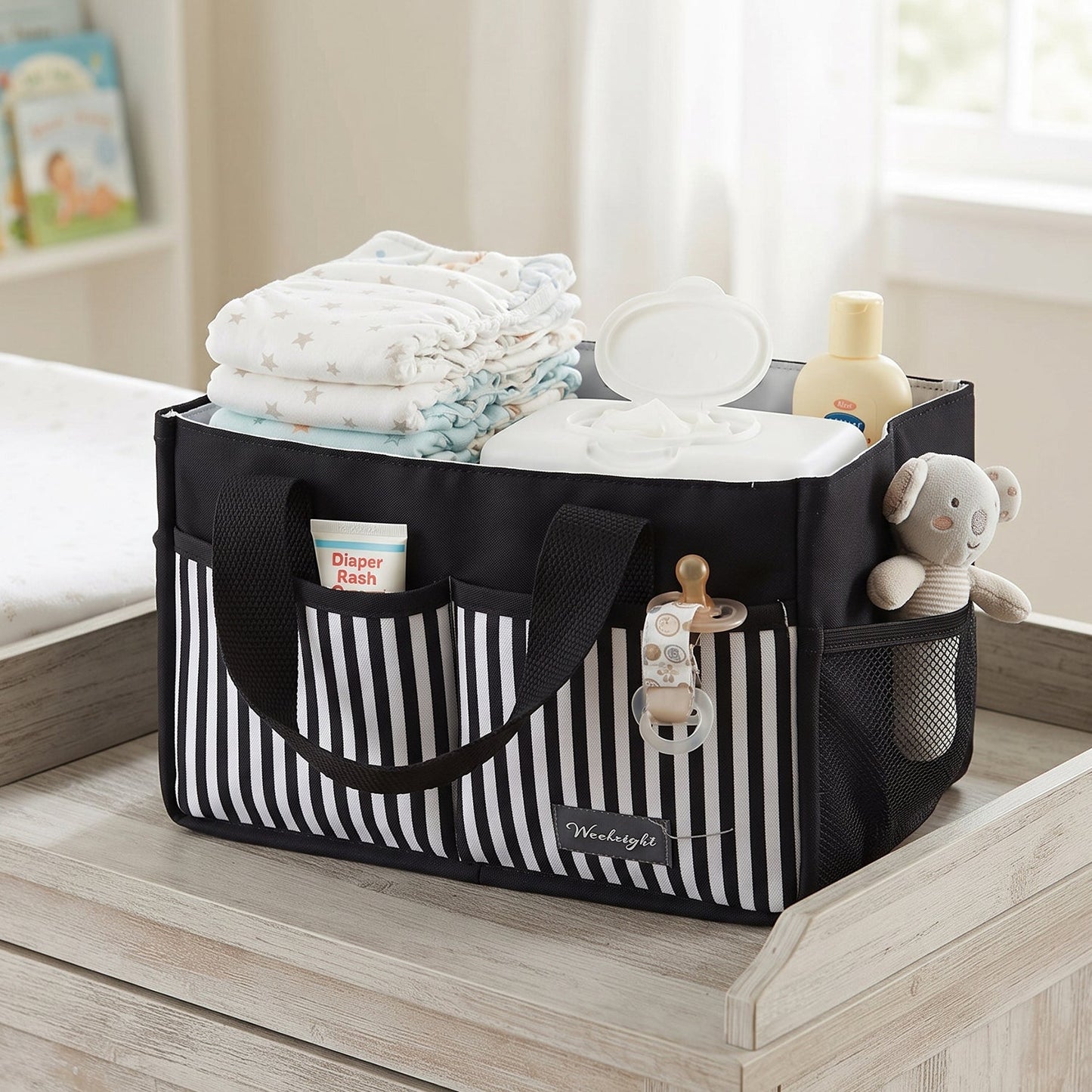 A black and white striped organizer bag caddy, filled with baby essentials, sits on a light wooden changing table.