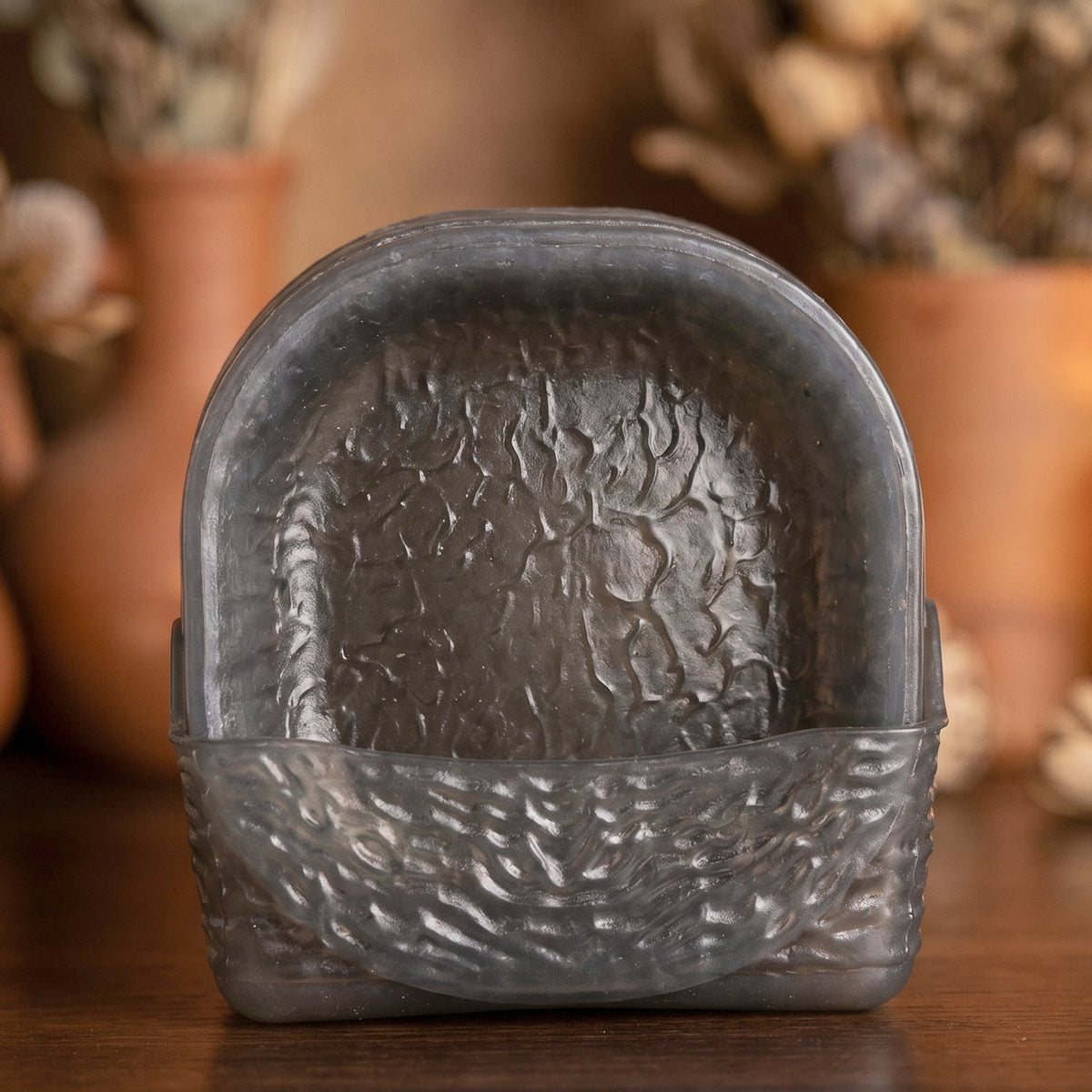 A dark gray textured glass storage basket holding several matching snack bowls upright, set against a blurred background.