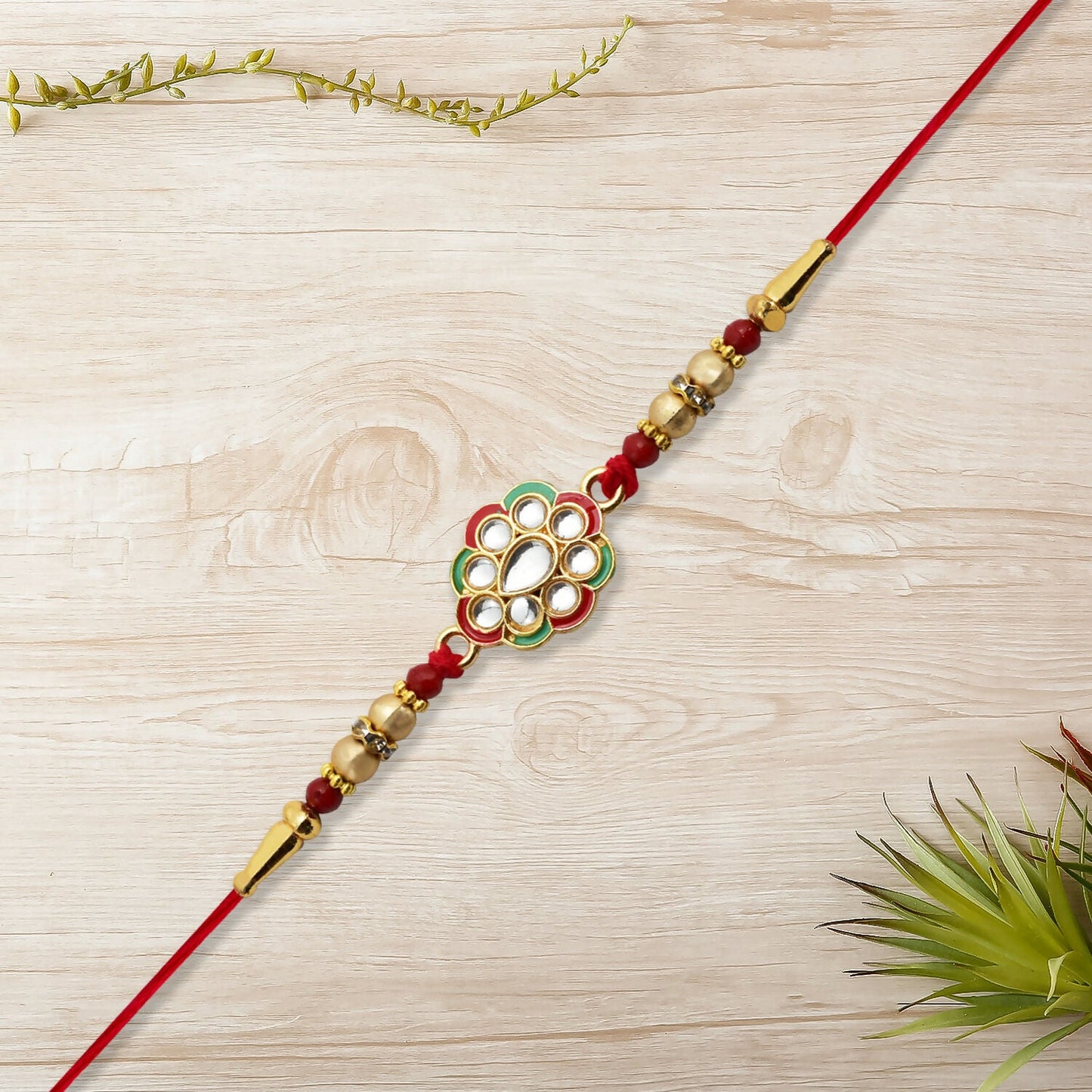 Detailed view of premium kundan work on floral rakhi with red cotton thread