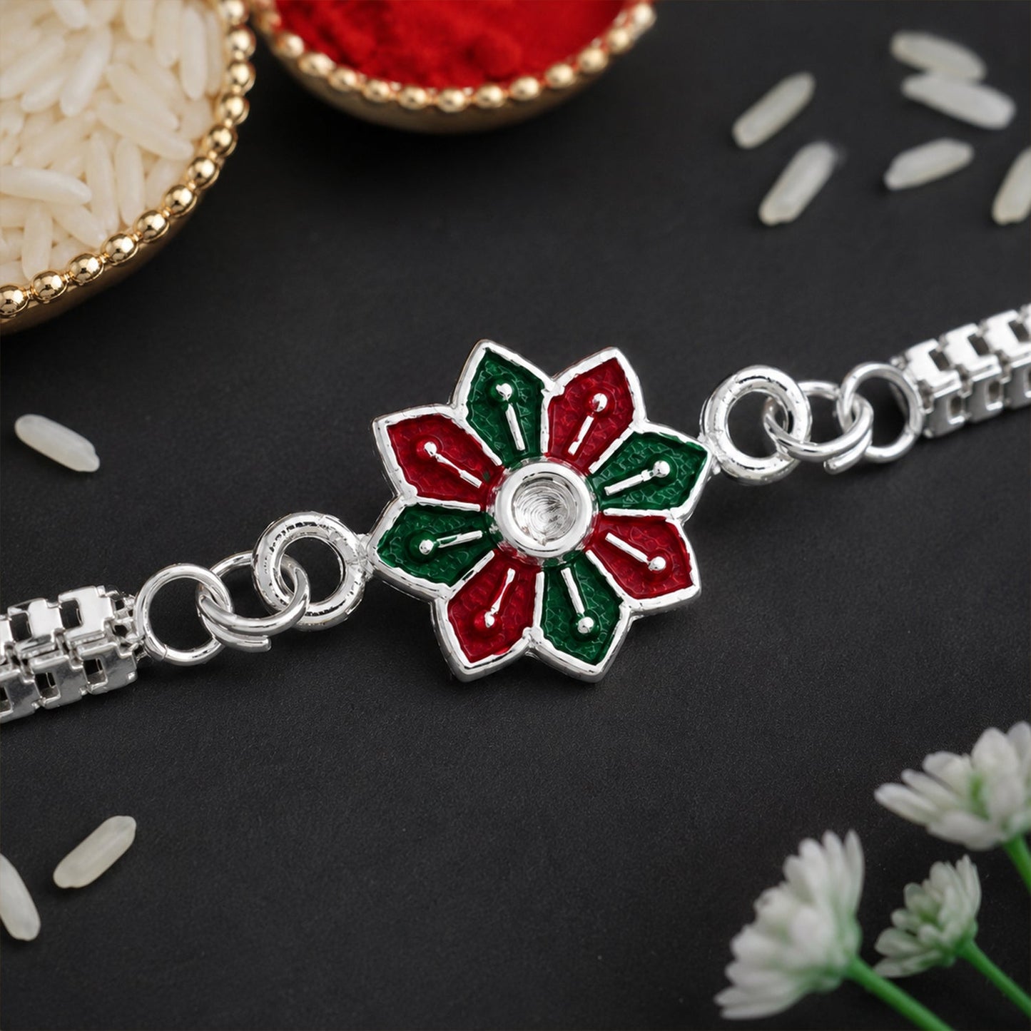 Elegant Silver Rakhi with intricate floral enamel design on a display stand.