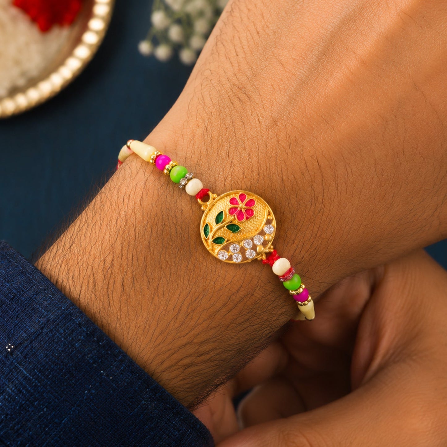 Close-up of flower design Rakhi featuring red and green beads with premium stones