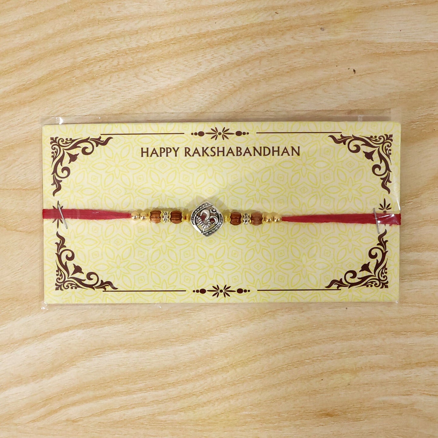 Hand holding the Om Rakhi demonstrating its fit and design.