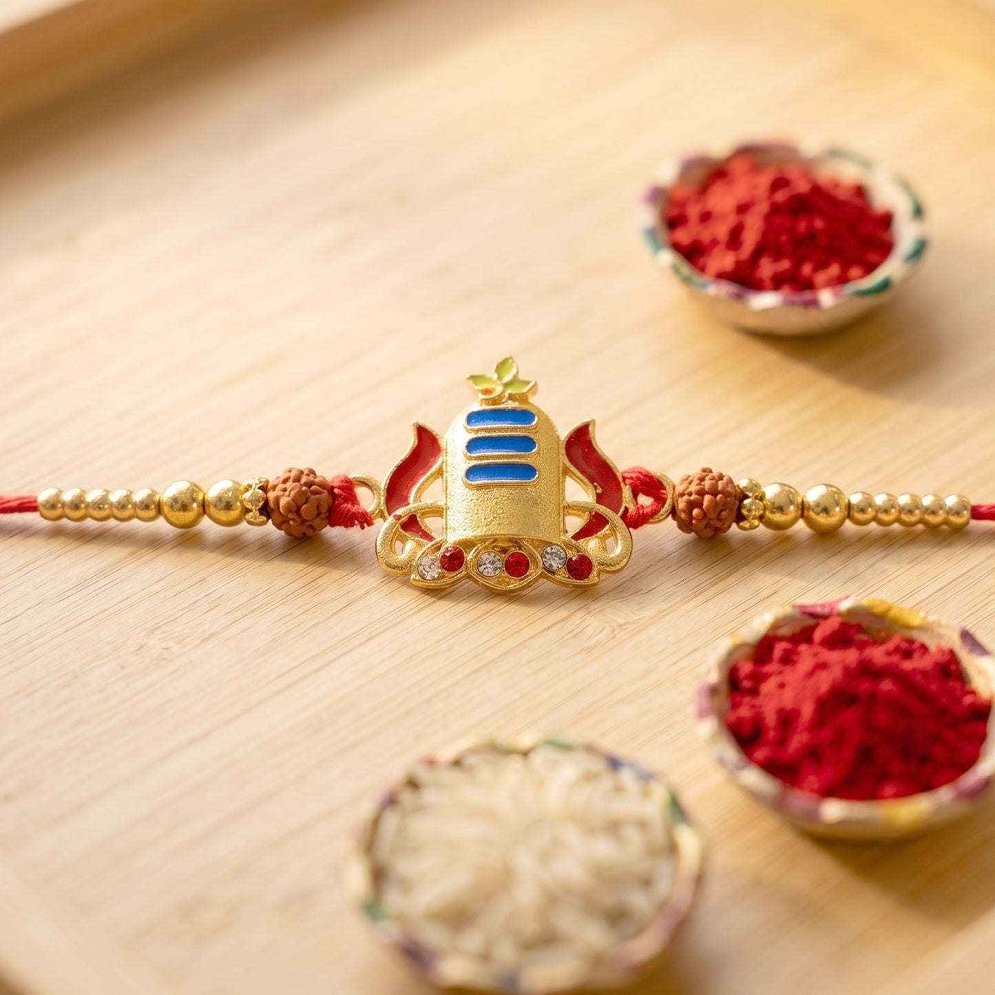 Festive gold shivling rakhi with blue tilak detail on display