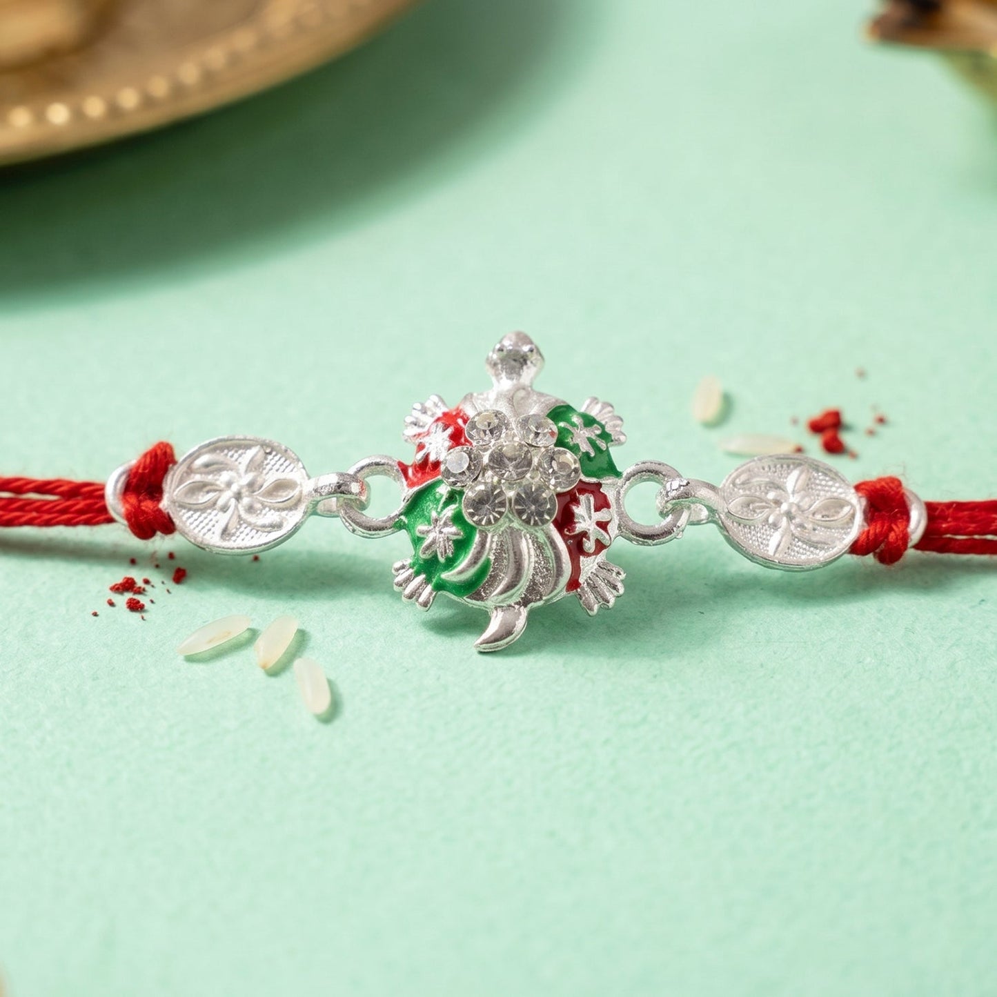 Side view of Turtle Rakhi showcasing beaded details and red thread.