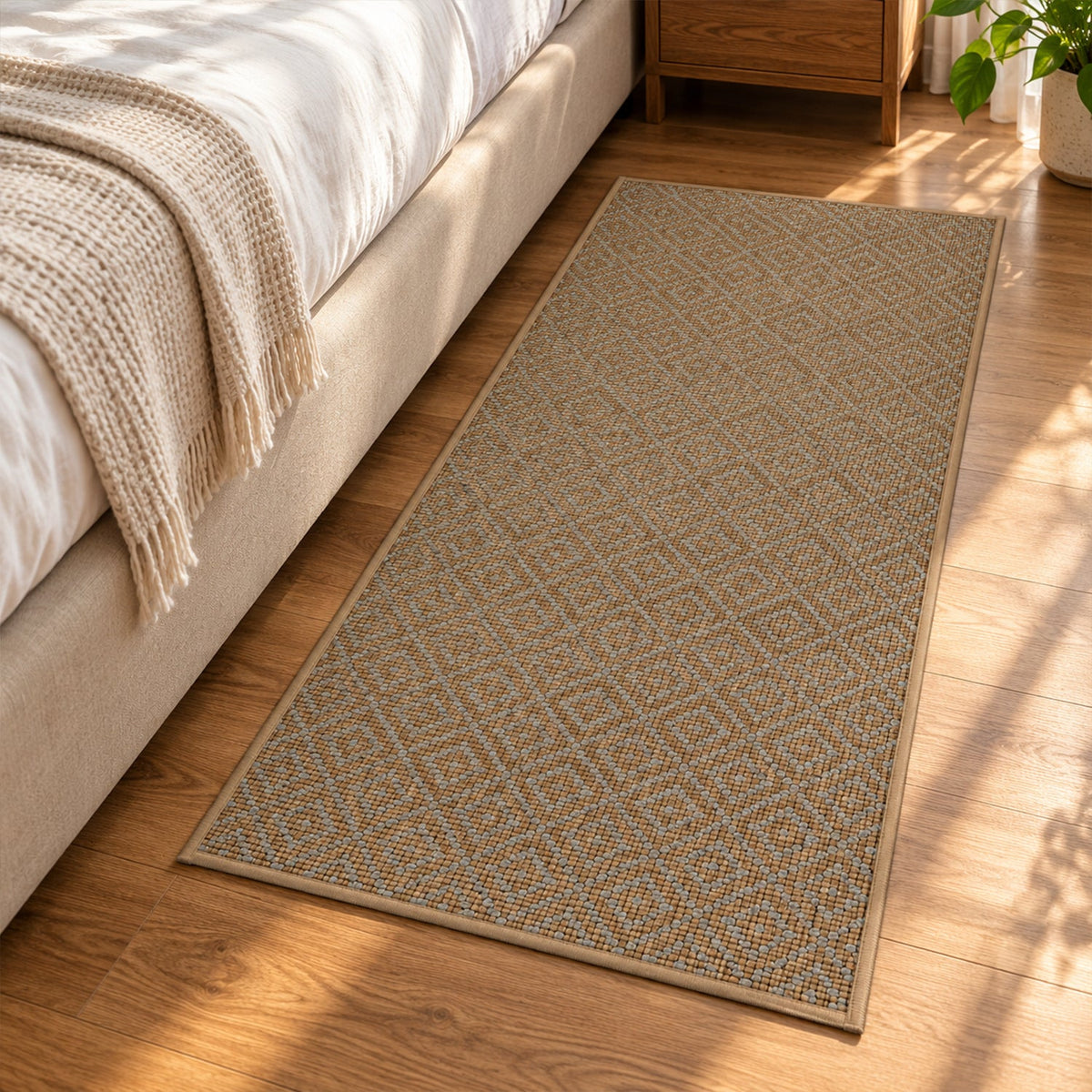 A brown diamond pattern runner mat lies on a wooden floor beside a bed with a beige blanket.