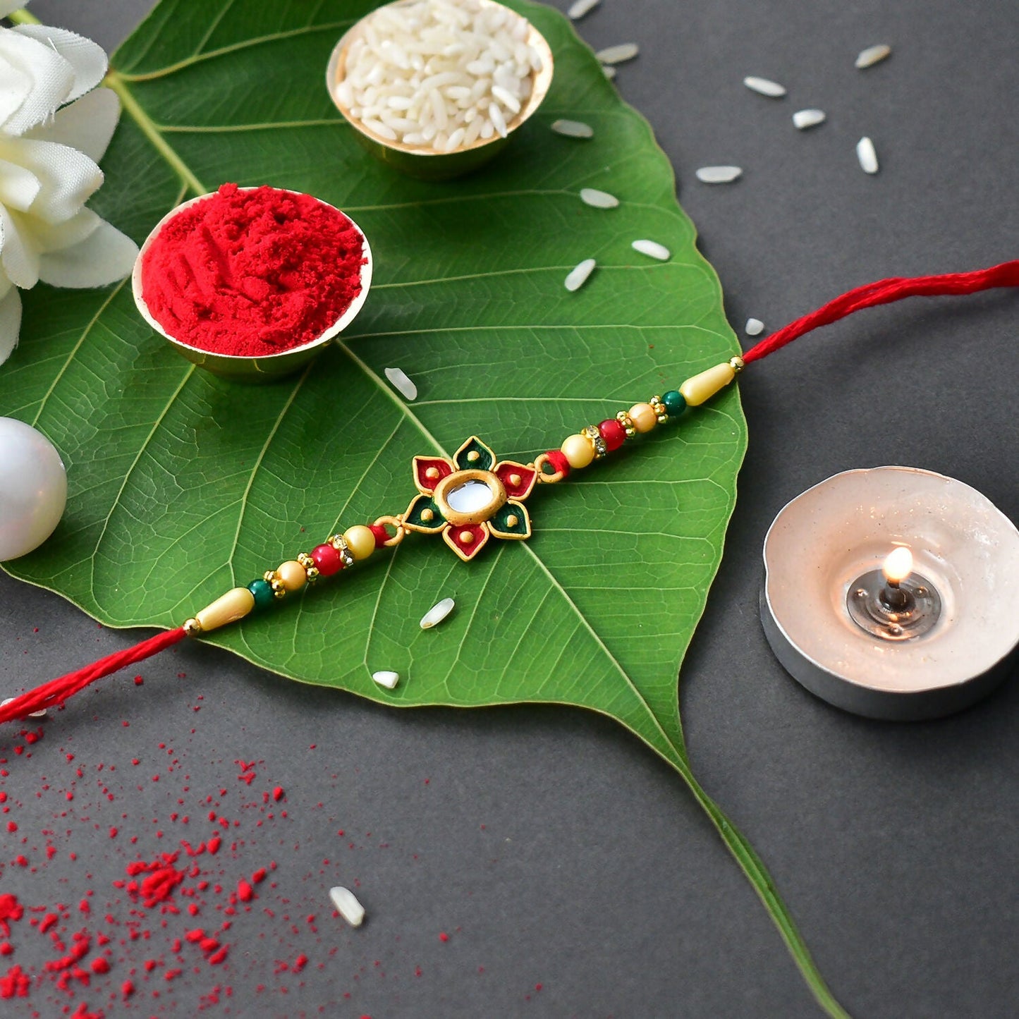 Detailed view of vibrant multicolor stone work on a floral Rakhi with red beaded thread