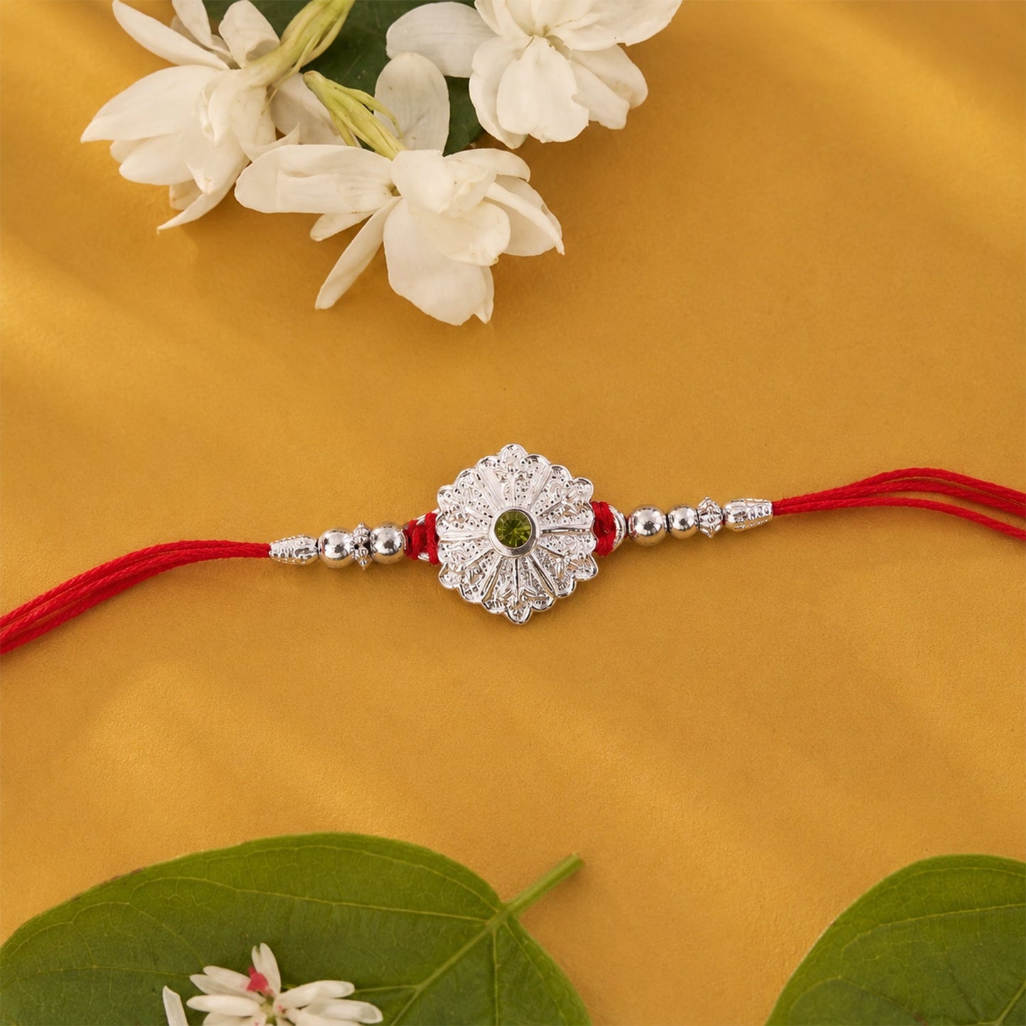 Decorative rakhi featuring green stone and intricate beaded design