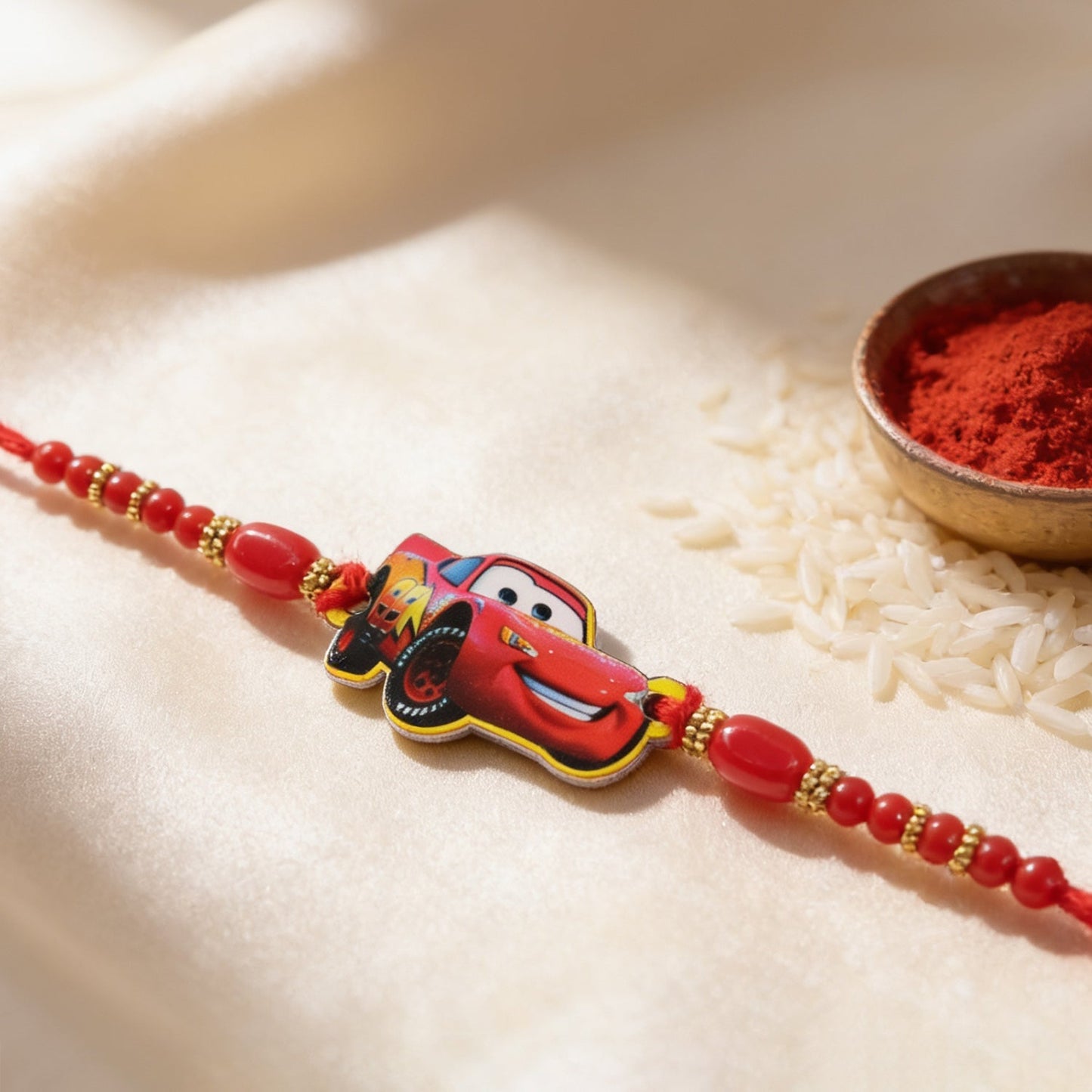 Close-up of racing car motif and gold bead accents on the rakhi.