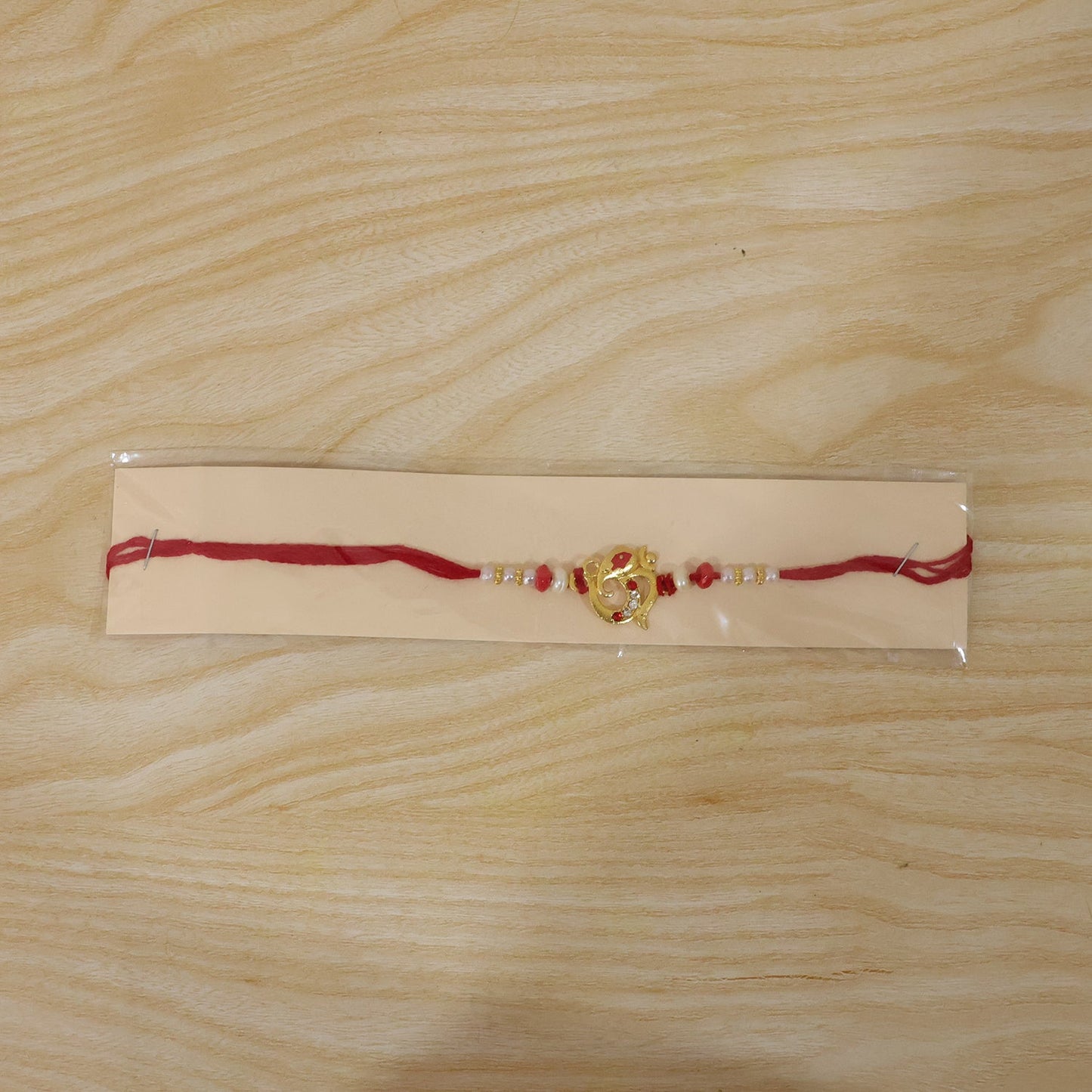 Beautifully crafted Rakhi featuring red beads and pearl dots designed for brothers