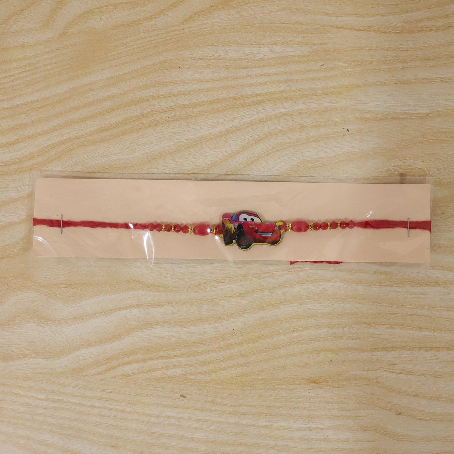 Close-up of red thread and gold beads on the rakhi.