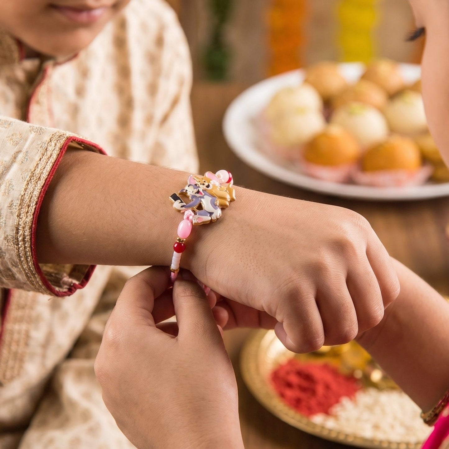 Close-up of Kids Rakhi with cartoon cat and mouse design and soft thread