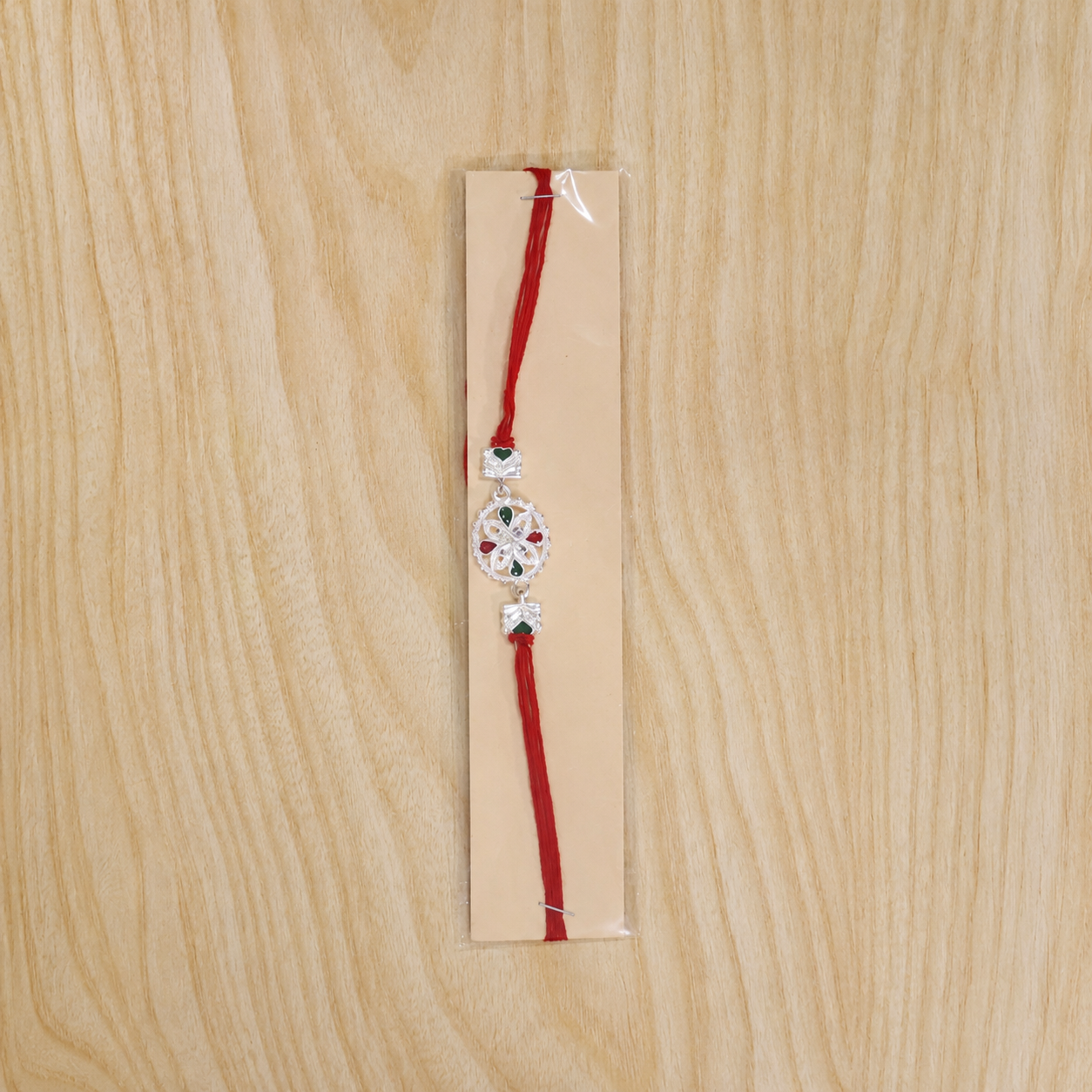 White silver floral rakhi with red stone, side view showcasing details