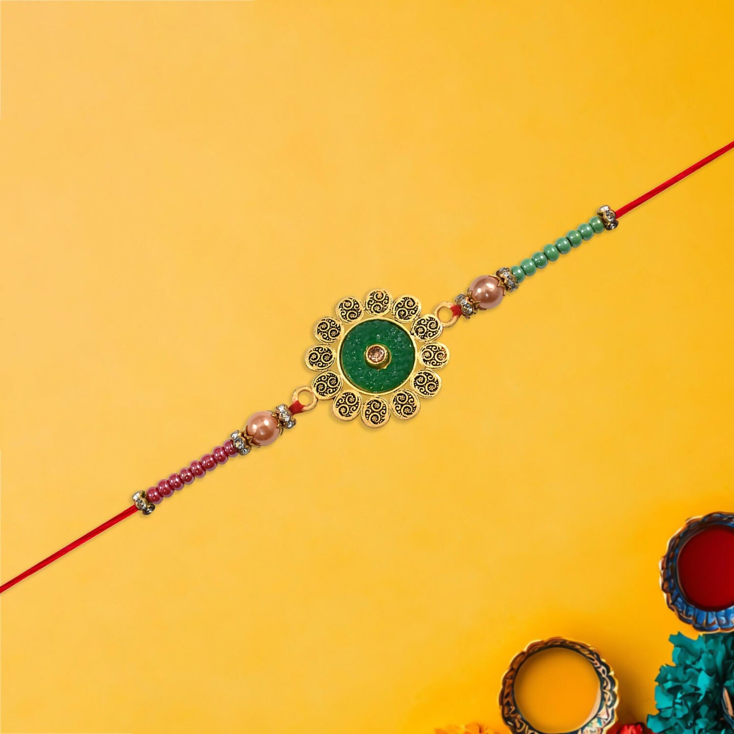 Hand holding floral Rakhi with green centerpiece and multicolor beads