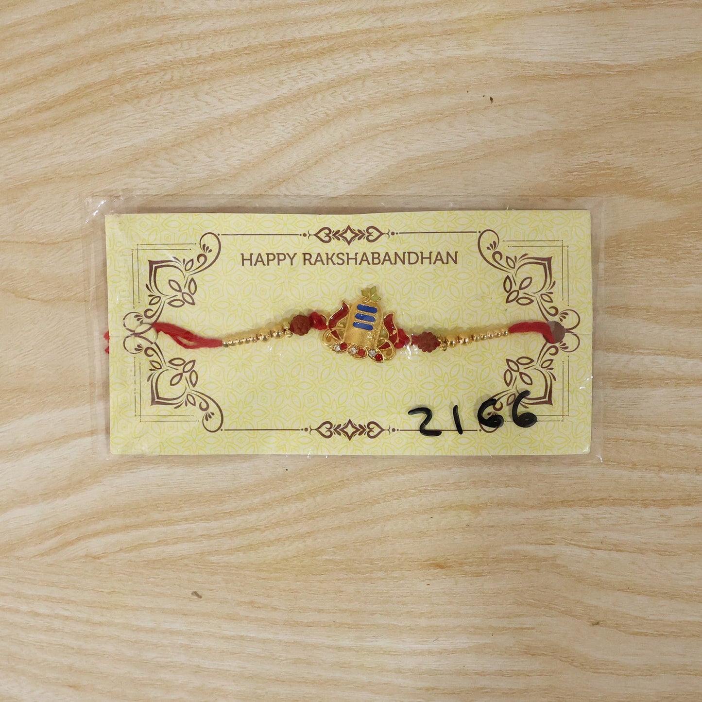 Stylish gold rakhi featuring blue tilak and rudraksha beads