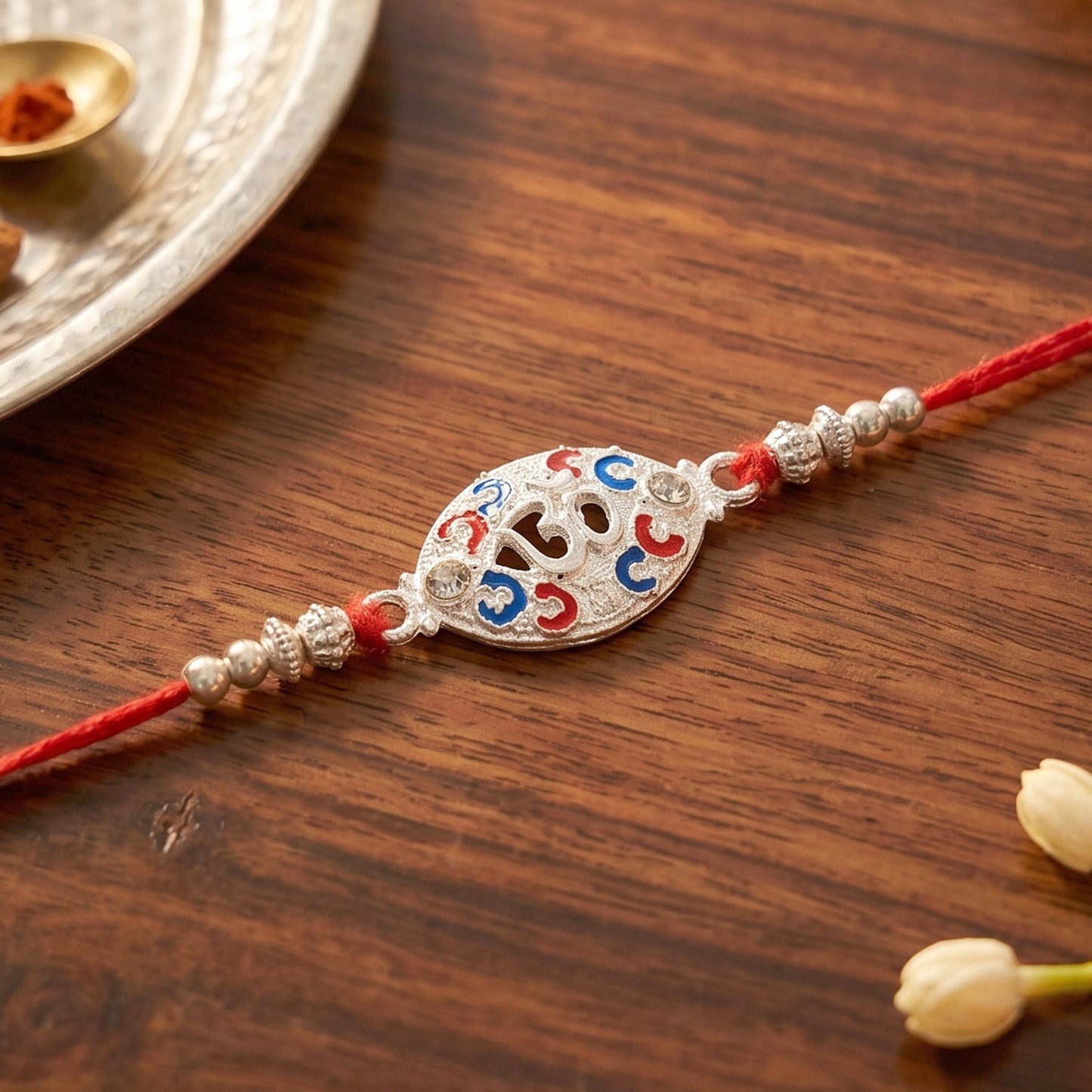 Elegant silver Om centerpiece of rakhi with vibrant decorative beads