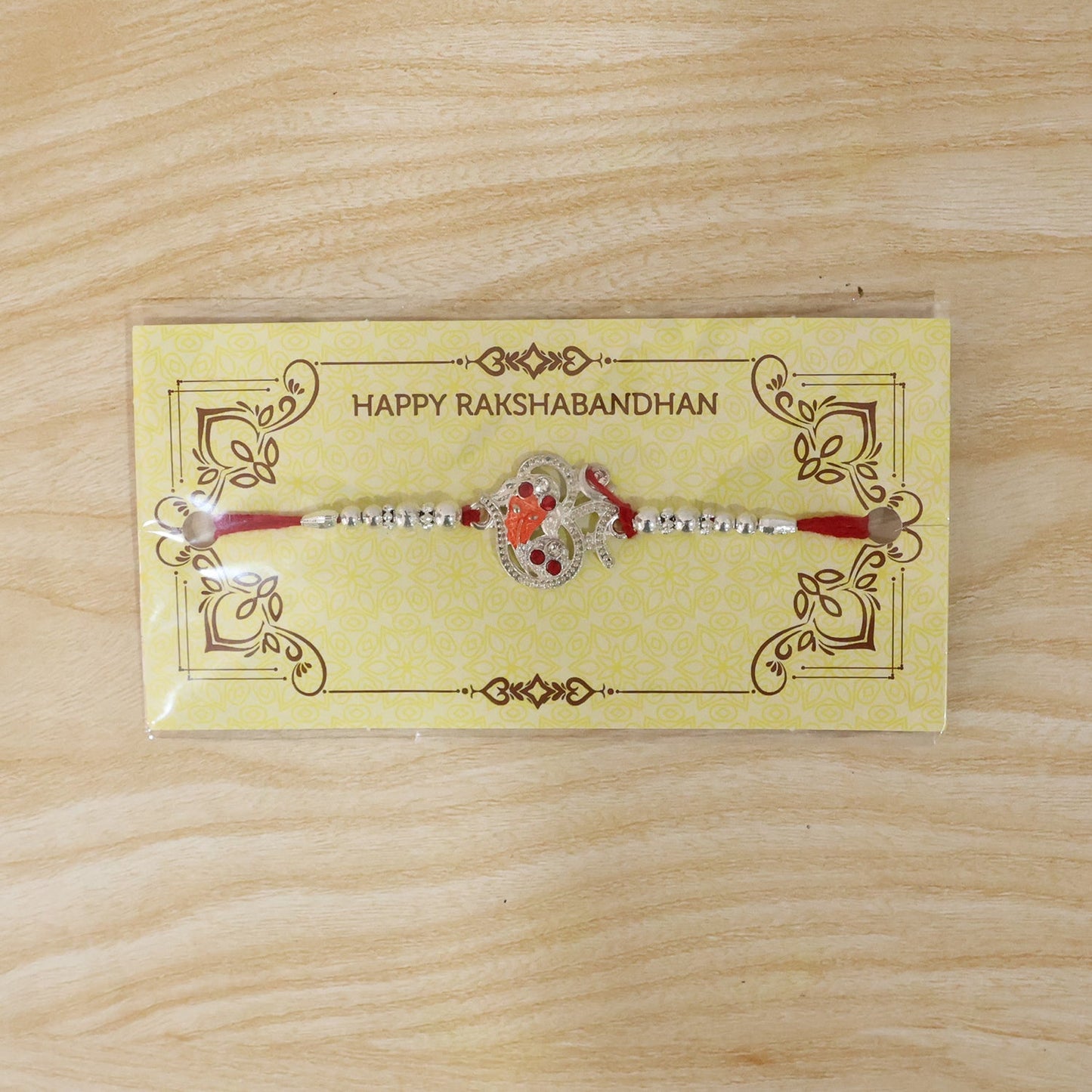 Close-up of Silver Om Ganesh Rakhi with thread and beads
