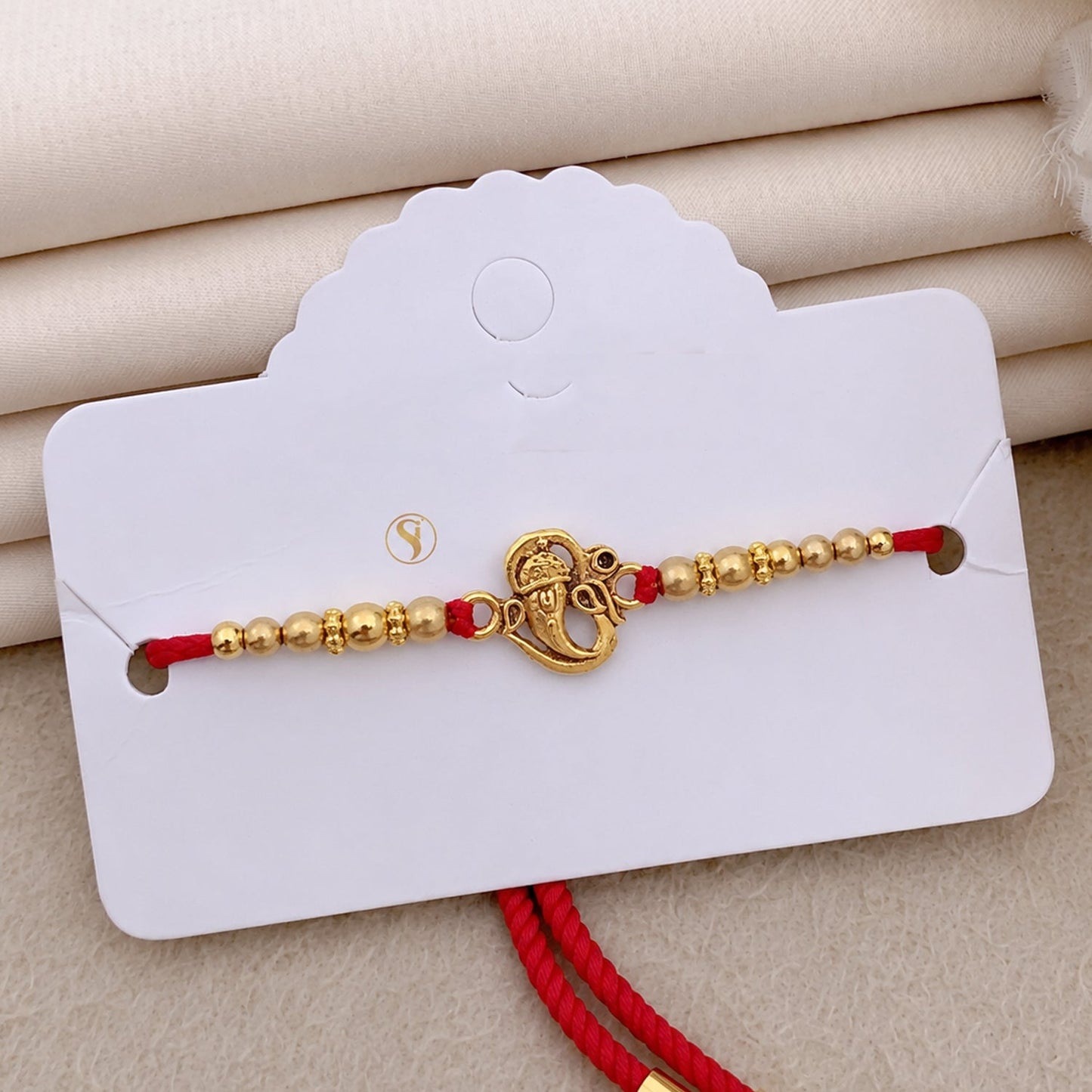 Top-down view of a designer Ganesha Rakhi with deity motif.