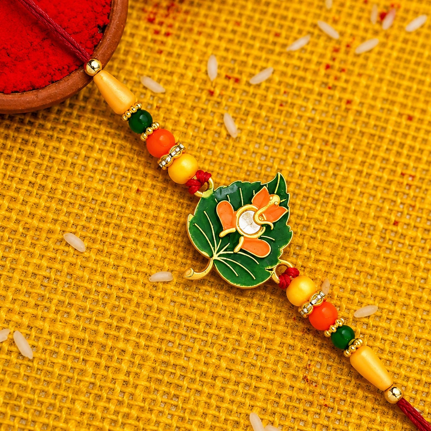 Green Tulsi leaf Rakhi with orange enamel flower on beaded thread