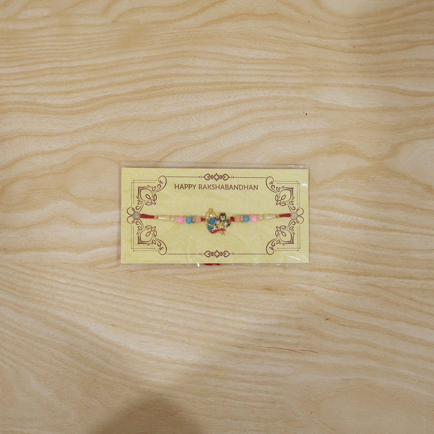 Full view of Peacock Rakhi with decorative thread