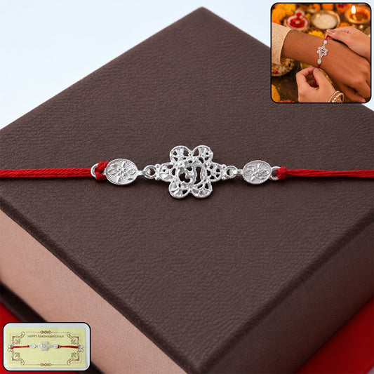Silver floral Om designer Rakhi with red thread on white background