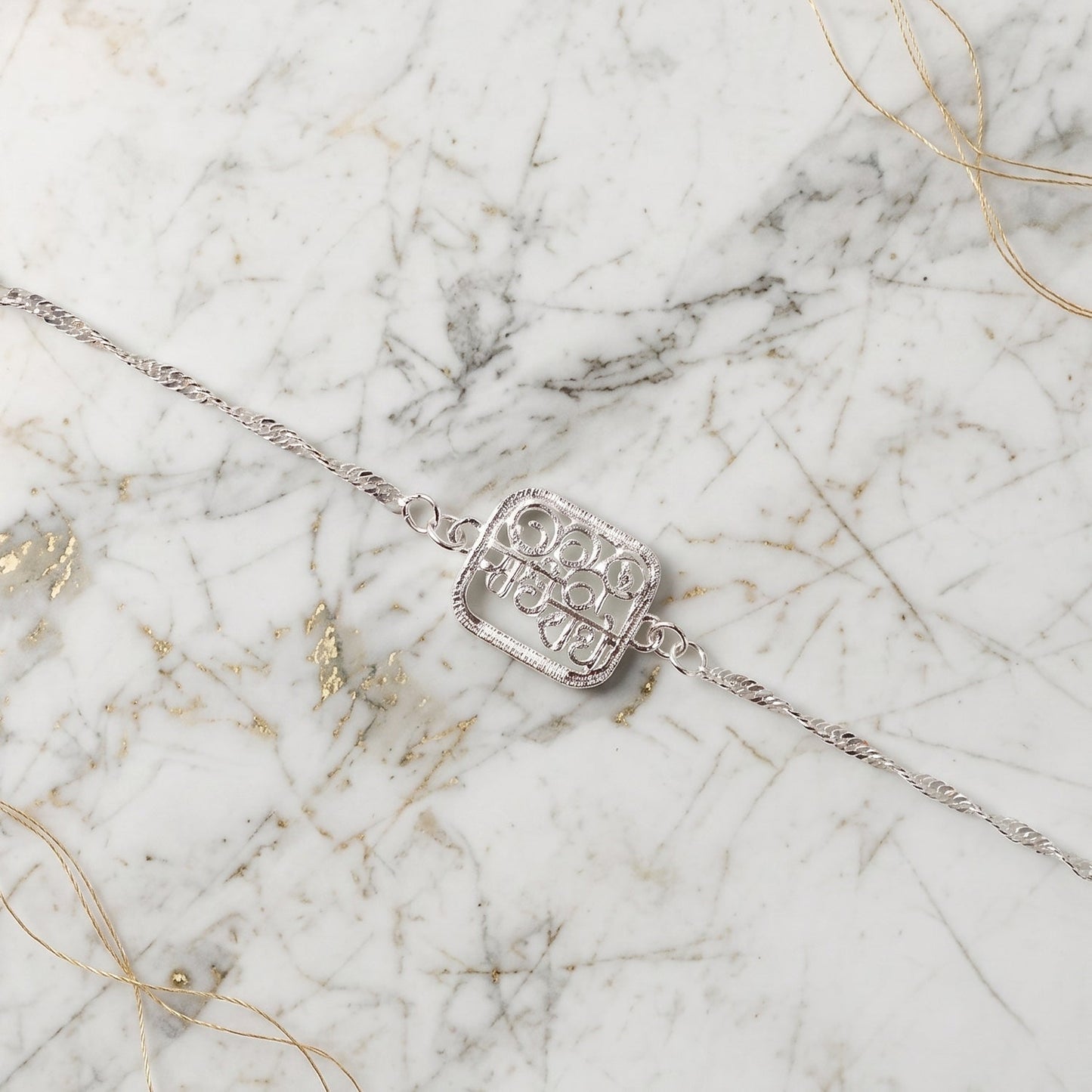 Silver Radhe Radhe Rakhi ready for gifting, shown tied in festive setting.