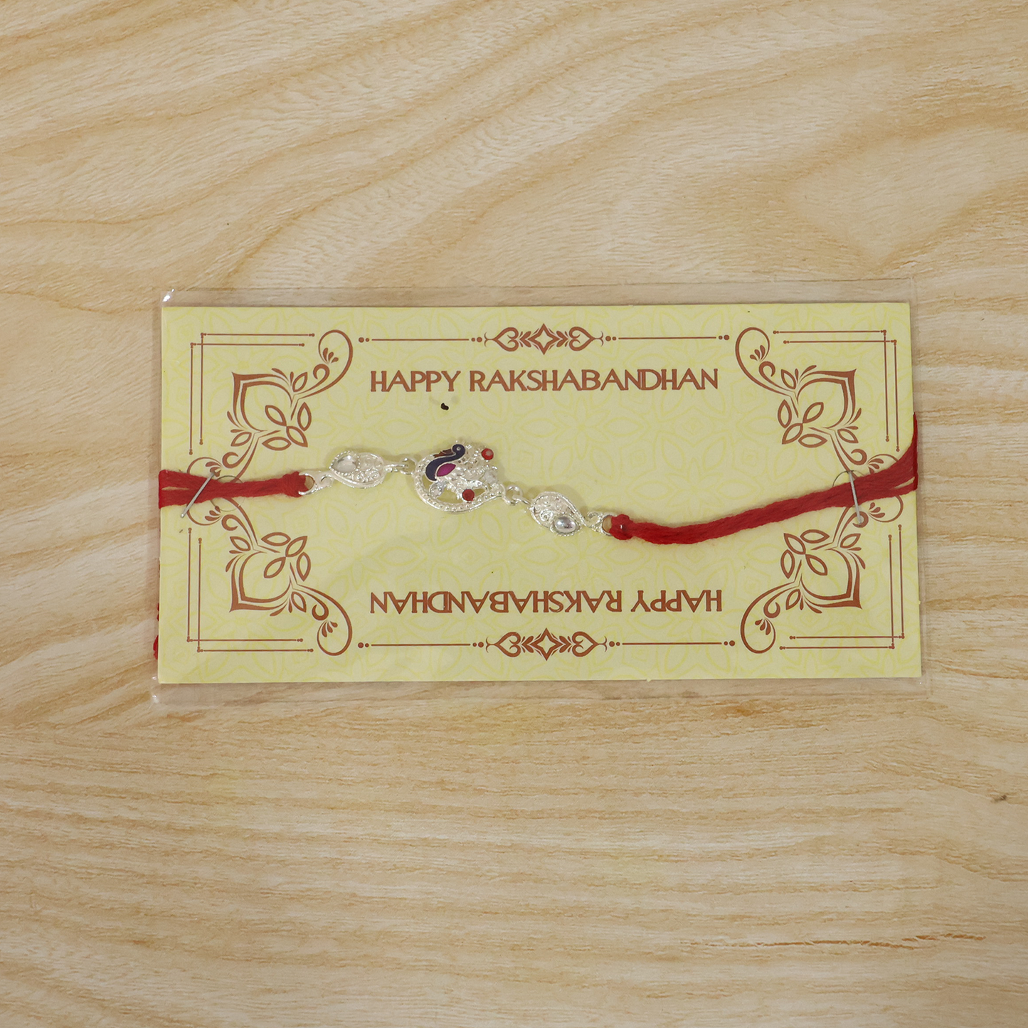 Vibrant red thread Rakhi with silver peacock charm