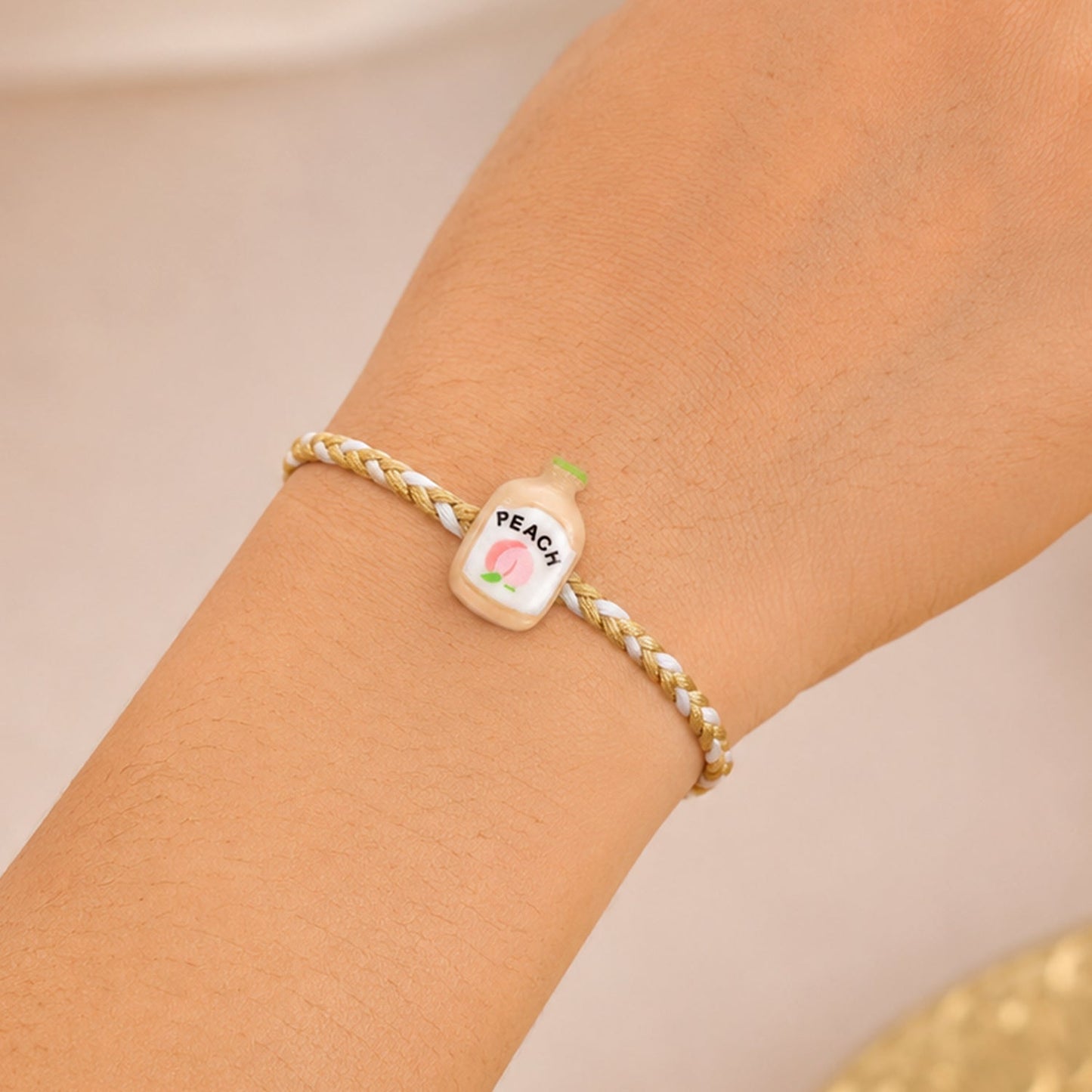 Close-up of the fancy dori and peach bottle charm detail on Rakhi