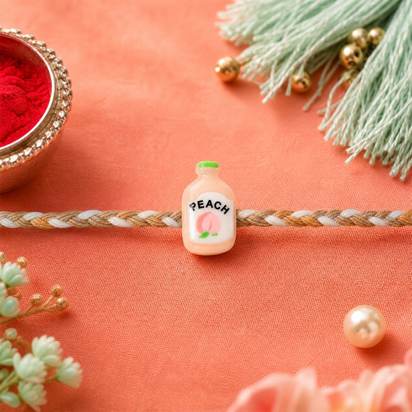 Neat finish of Peach Bottle Charm Rakhi with eye-catching design