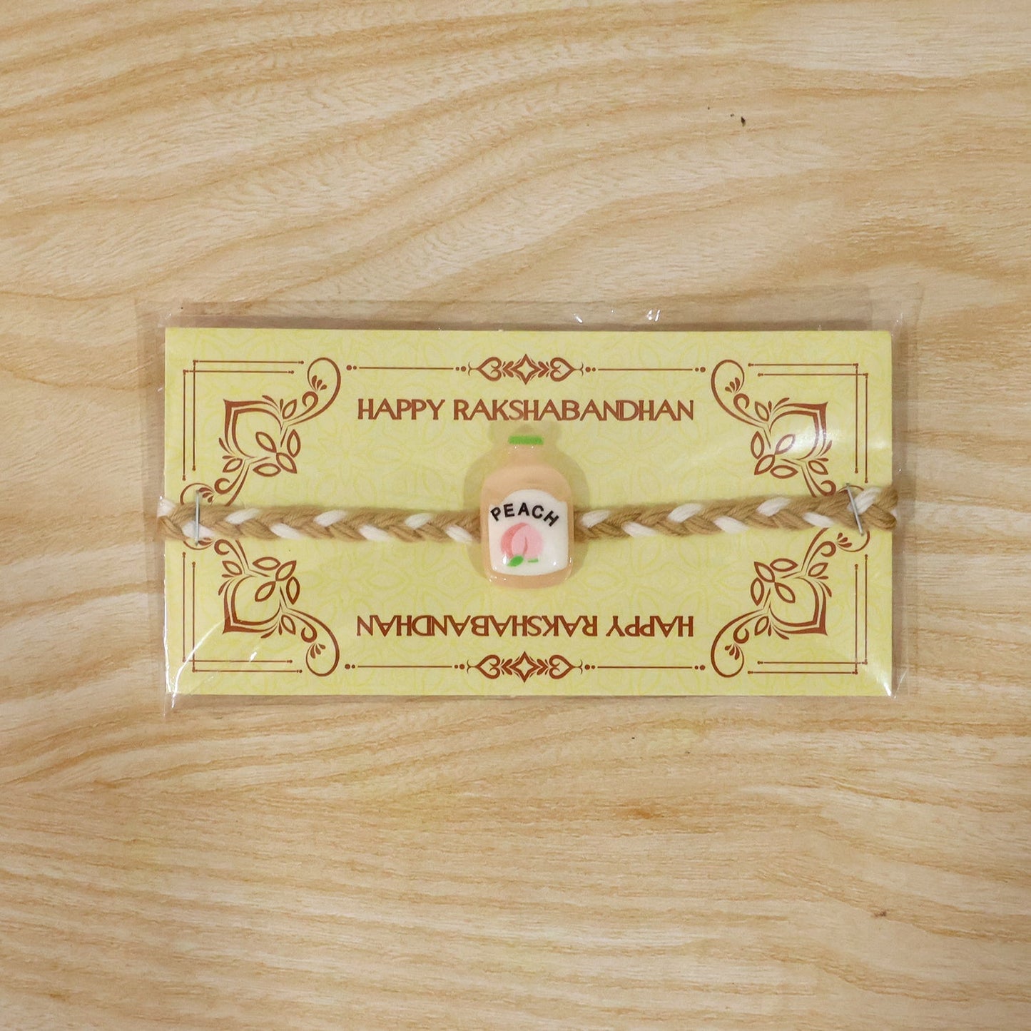 Decorative peach bottle charm on Rakhi string, vibrant and appealing